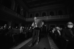 Czarno-białe zdjęcie. Marcin Wyrostek idący środkiem sali koncertowej