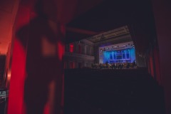 Kolorowo oświetlona scena widoczna  z tyłu sali