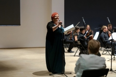 Regina Gowarzewska zapowiadająca koncert, w tle orkiestra