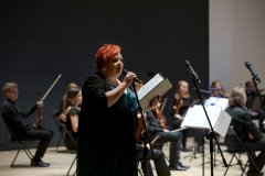 Regina Gowarzewska zapowiadająca koncert, w tle orkiestra