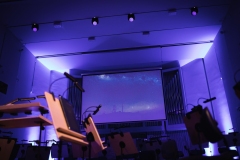Widok na scenę podświetloną niebieskimi światłami, na ekranie grafika przedstawiająca kosmos