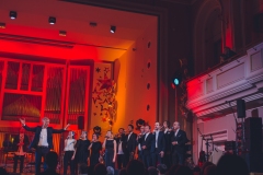 Muzycy na scenie oświetlonej w czerwono-pomarańczowych barwach