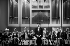 Czarno-białe zdjęcie. Orkiestra oraz Yaroslav Shemet podczas oklasków, zwróceni w stronę publiczności