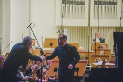 Piotr Sałajczyk podczas uścisku dłoni z koncertmistrzem orkiestry
